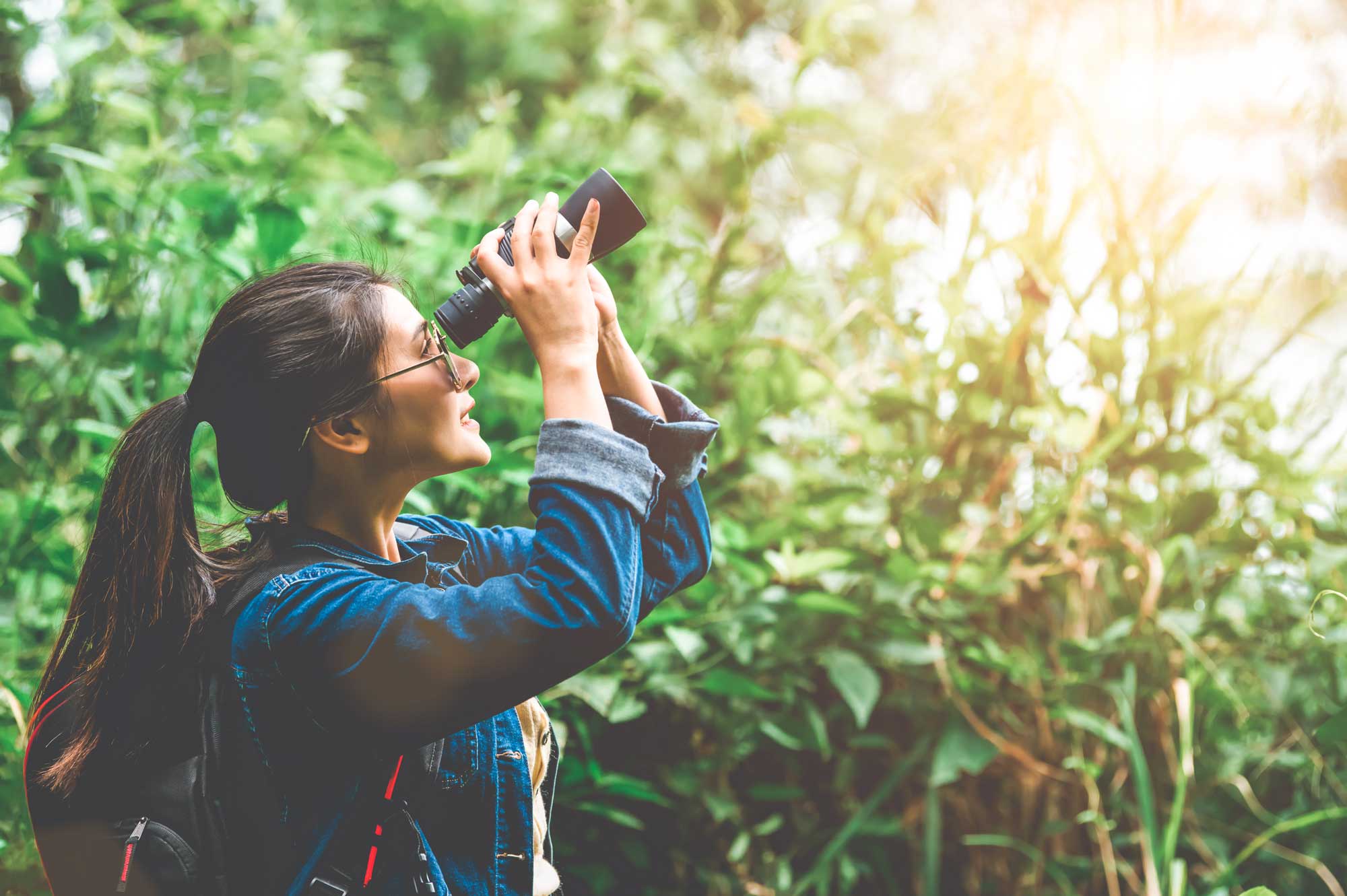 woman with binoculars telescope in forest looking destination