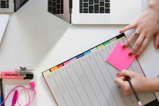 person holding pencil and stick note beside table by Marten Bjork courtesy of Unsplash.