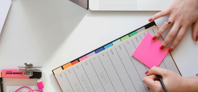 person holding pencil and stick note beside table by Marten Bjork courtesy of Unsplash.